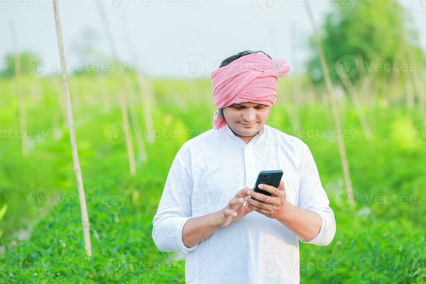 Young indian farmer showing Smart phone , Farmer talking on phone in farm, happy indian farmer photo