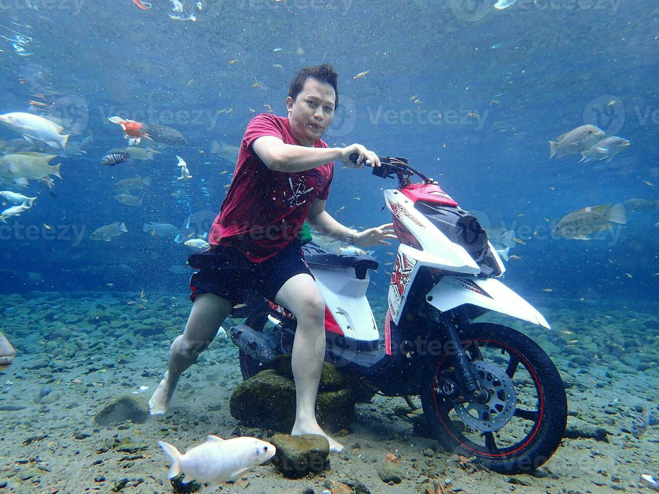 Klaten, Umbul ponggok, Indonesia, July 22, 2022,  a man taking a photo under clear water