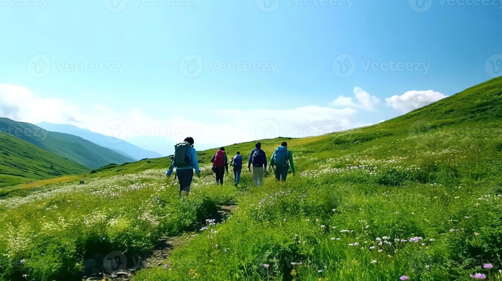 Group of hikers walks in green mountains with blue sky . photo