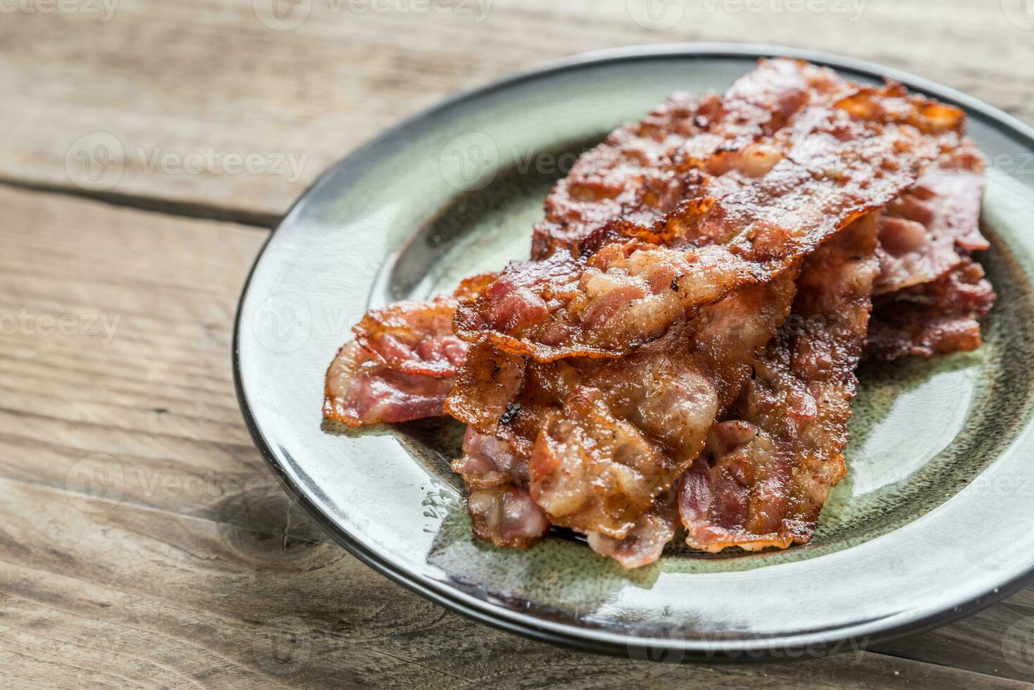 Stack of fried bacon strips on the plate photo