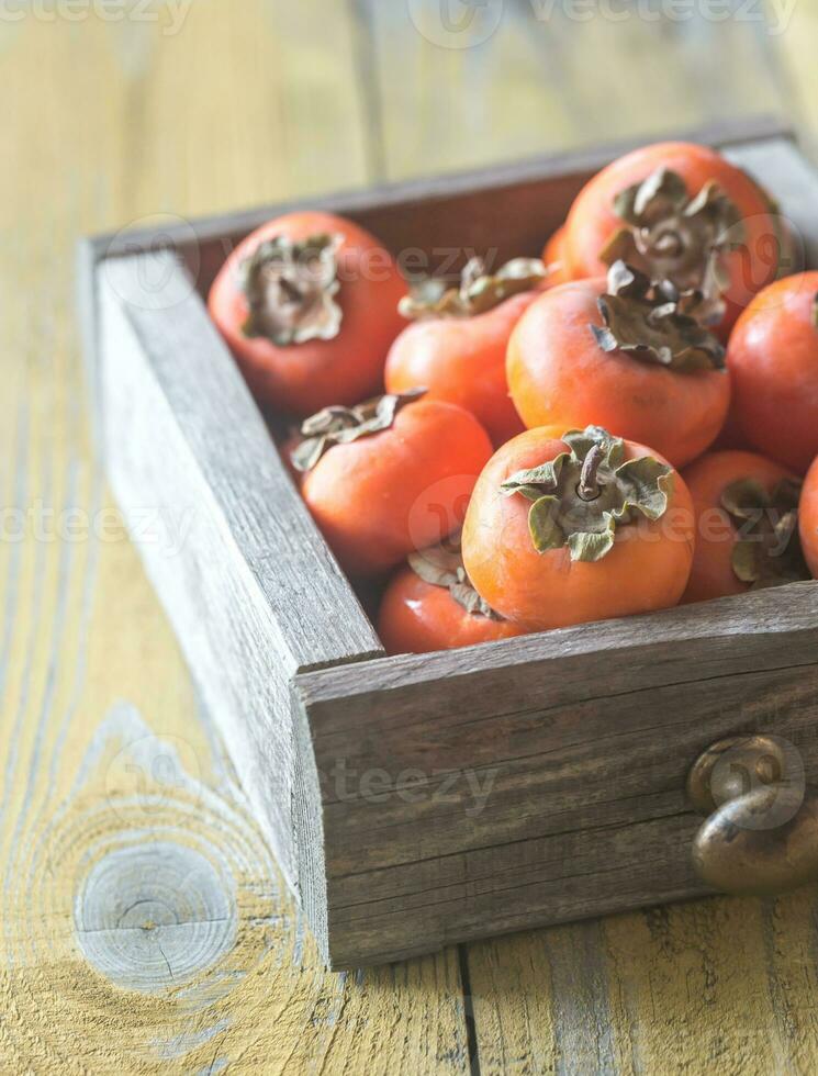 Wooden box of fresh persimmons photo