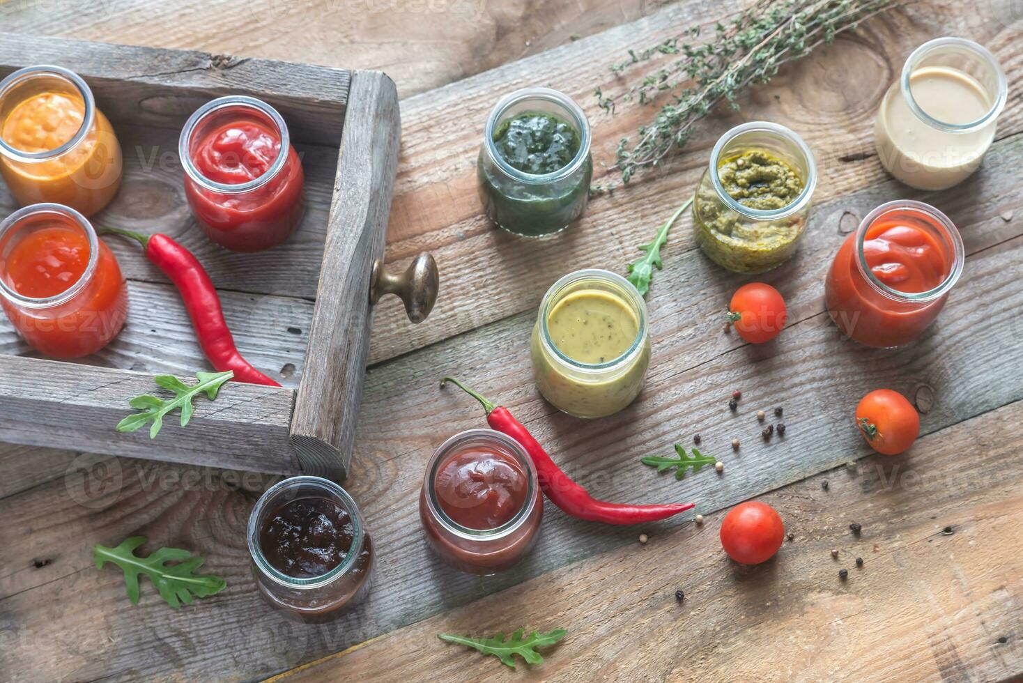 Assortment of sauces in the glass jars with ingredients photo