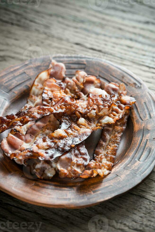 Fried bacon strips on the plate photo