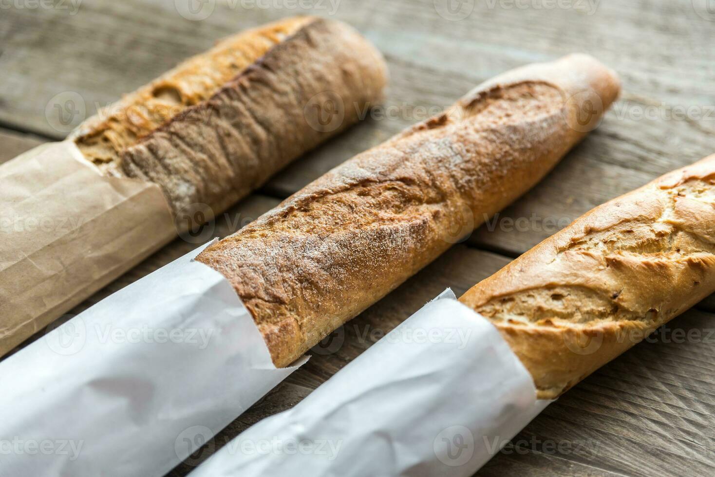 Three baguettes on the wooden background photo