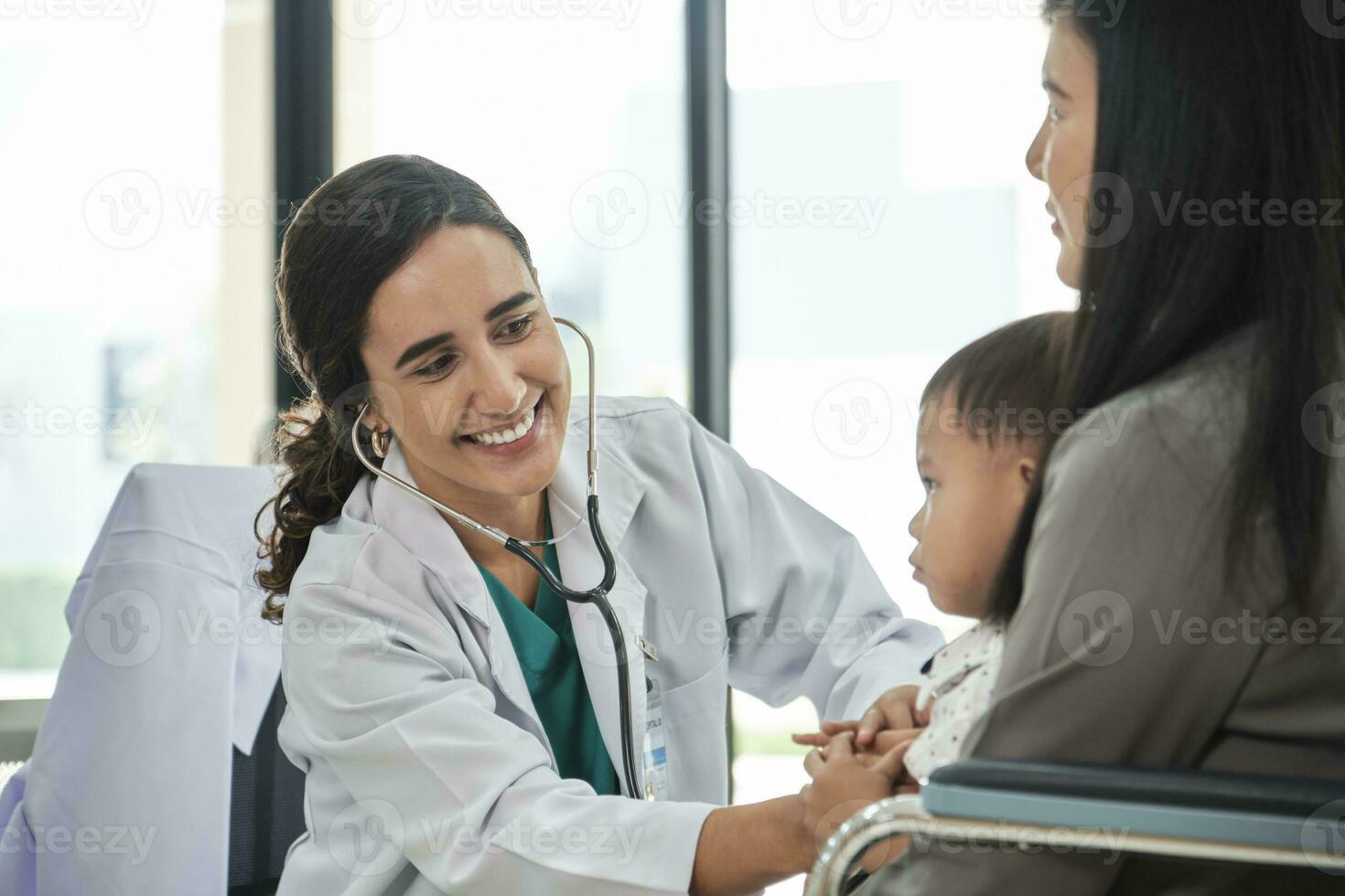 Young female pediatric doctor teases little Asian boy before medical examination at outpatient clinic hospital, people public health care checkups, and appointment visits. photo