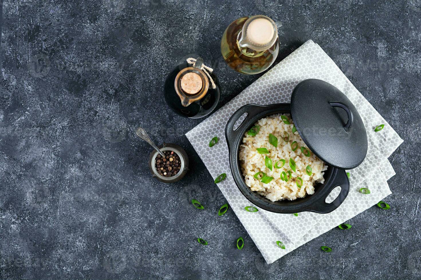 Stewed rice with chicken in a pot on dark grey background. Top view photo