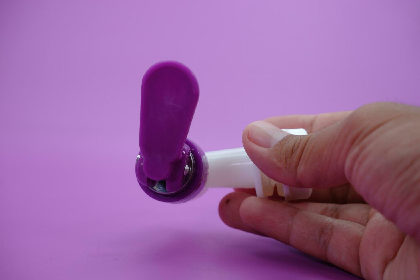 hand holding faucet isolated purple background. photo