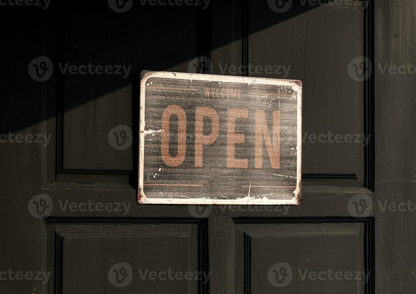 Sign with message Welcome OPEN on black wooden door photo