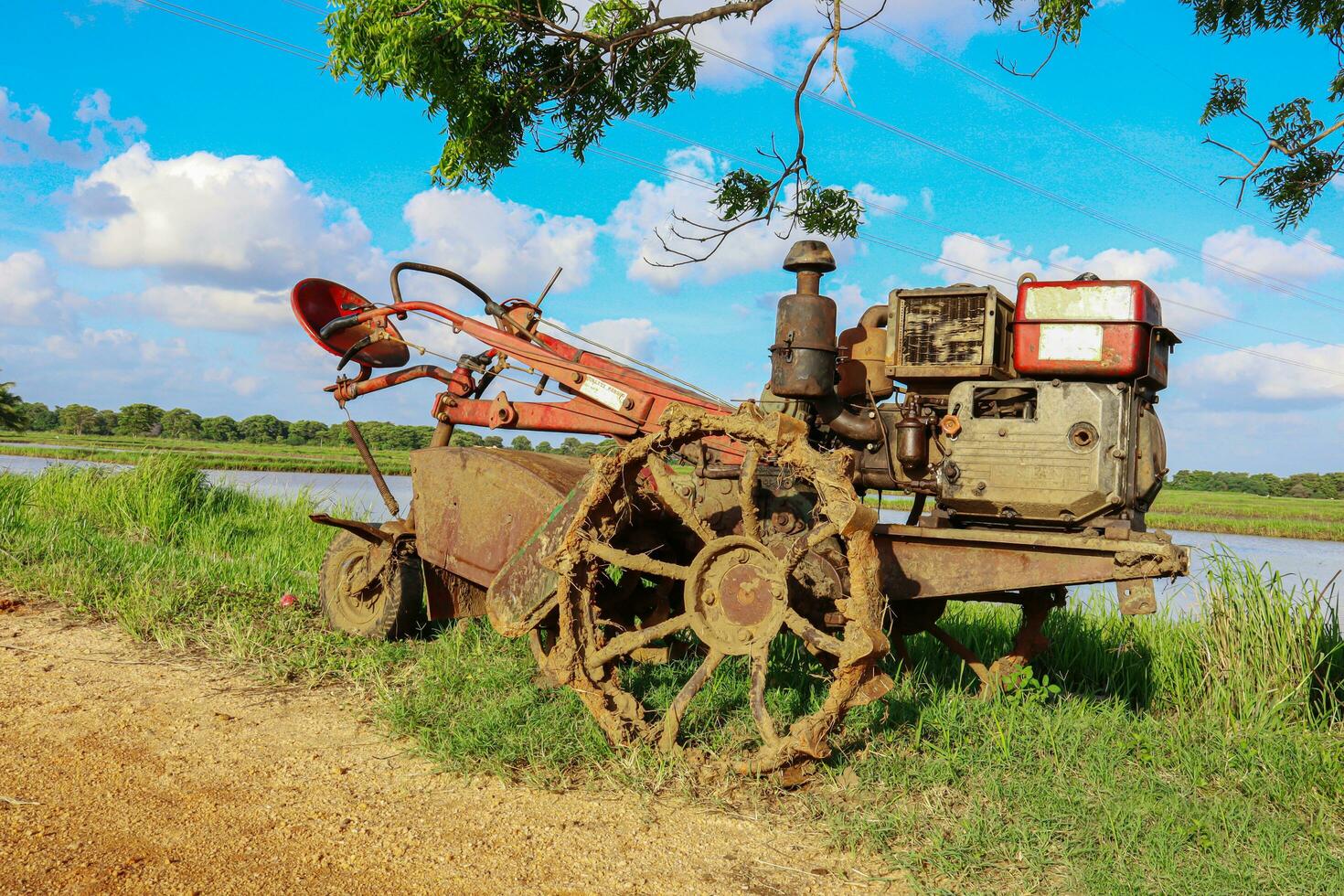 Old rusty tractor on the field with blue sky background. photo