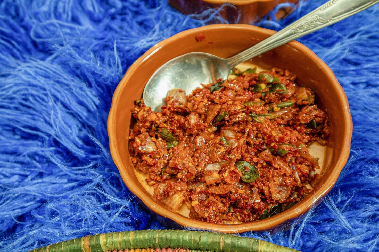 Spicy minced meat salad in a clay bowl on a blue background photo