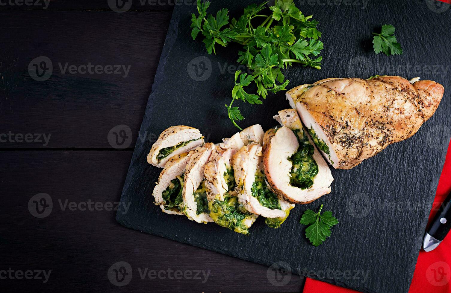 Roasted sliced Christmas roll of turkey with spinach and cheese on dark rustic background. Top view, copy space. Festival food. photo