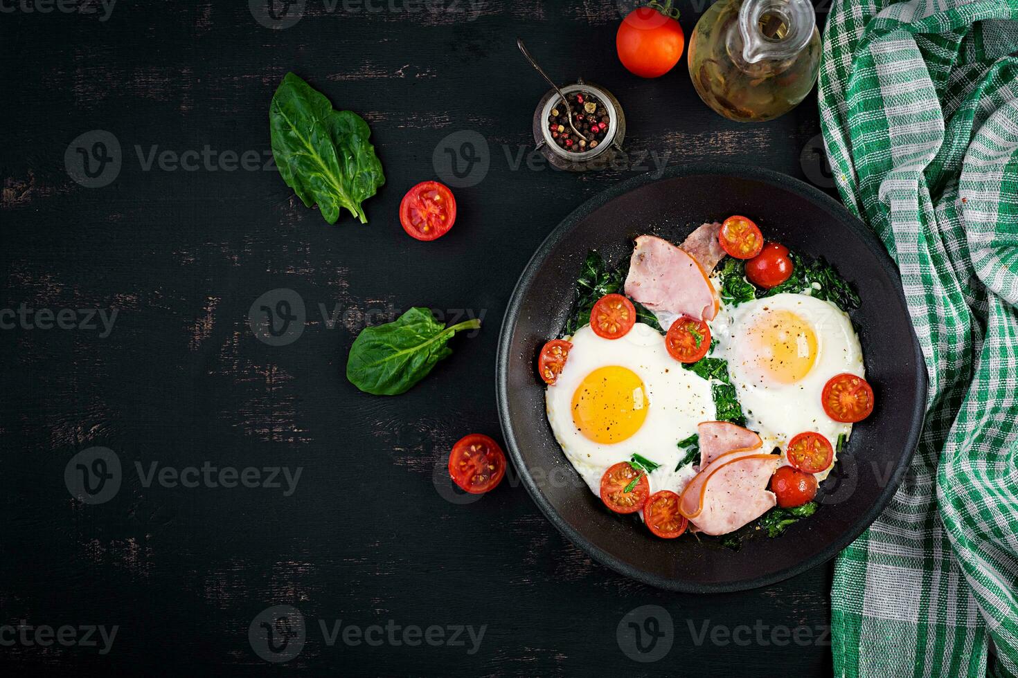 Plate with a keto diet food. Fried egg, ham, spinach, and tomatoes. Keto, paleo breakfast. Top view, copy space photo