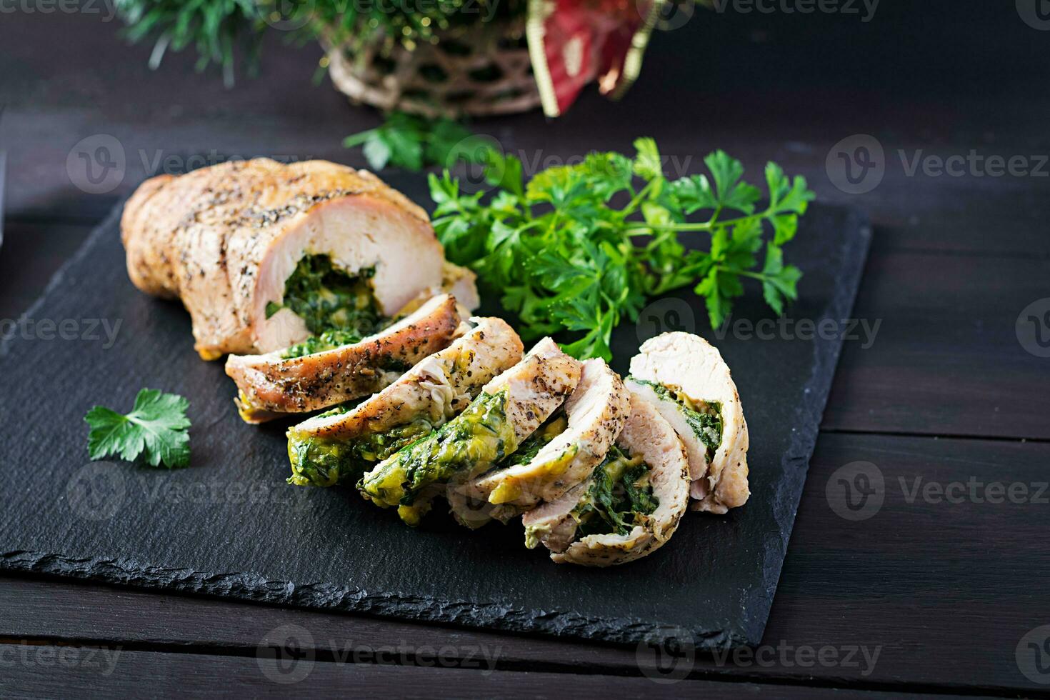 Roasted sliced Christmas roll of turkey with spinach and cheese on dark rustic background.  Festival food. photo