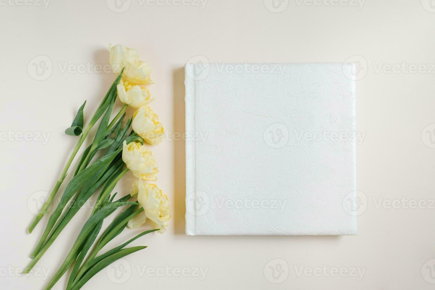 Composition with a wedding or family photo album, a bouquet of flowers of yellow tulips on a light background. Flat lay, top view still life.