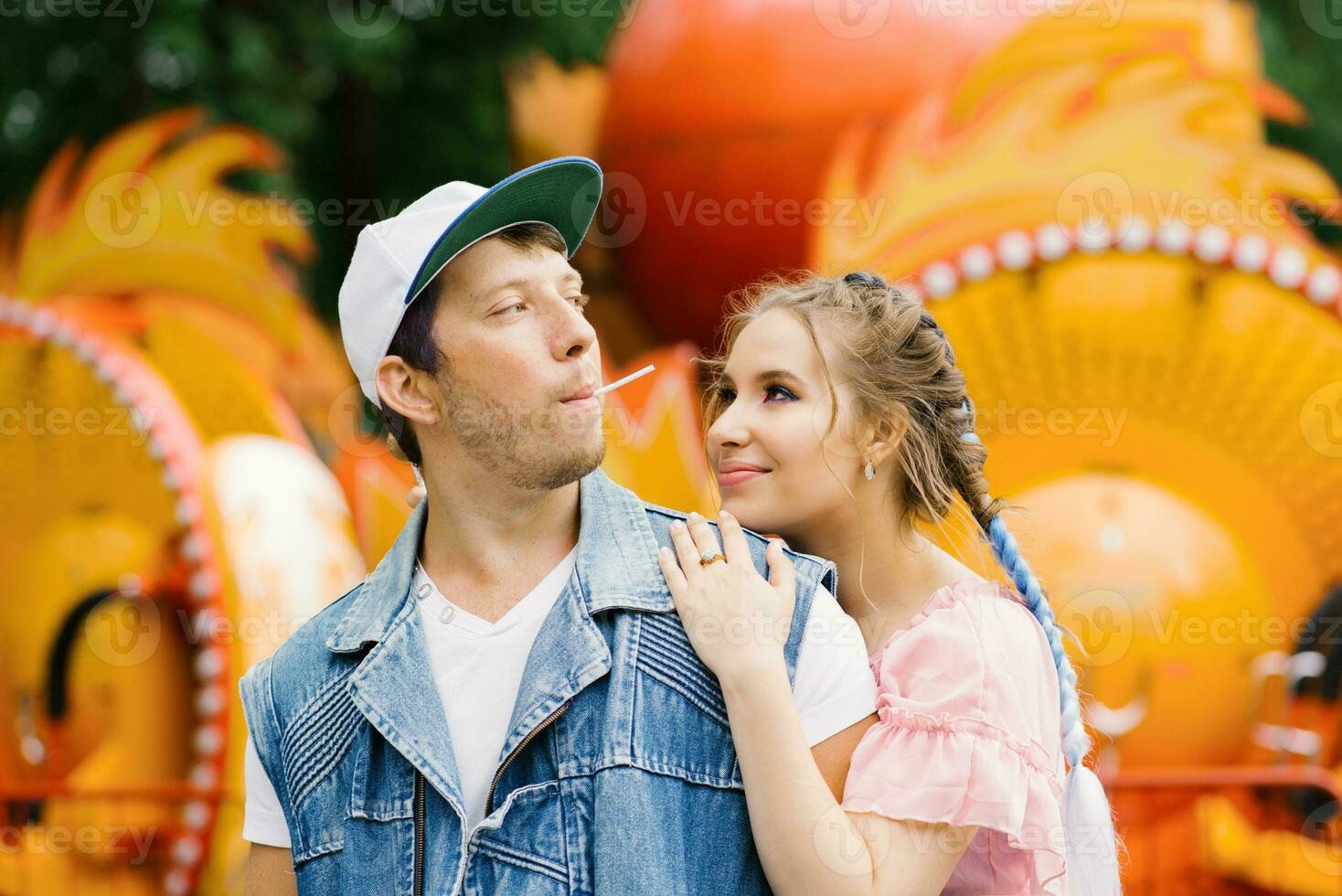 Happy couple in love having fun in an amusement park, eating lollipops photo