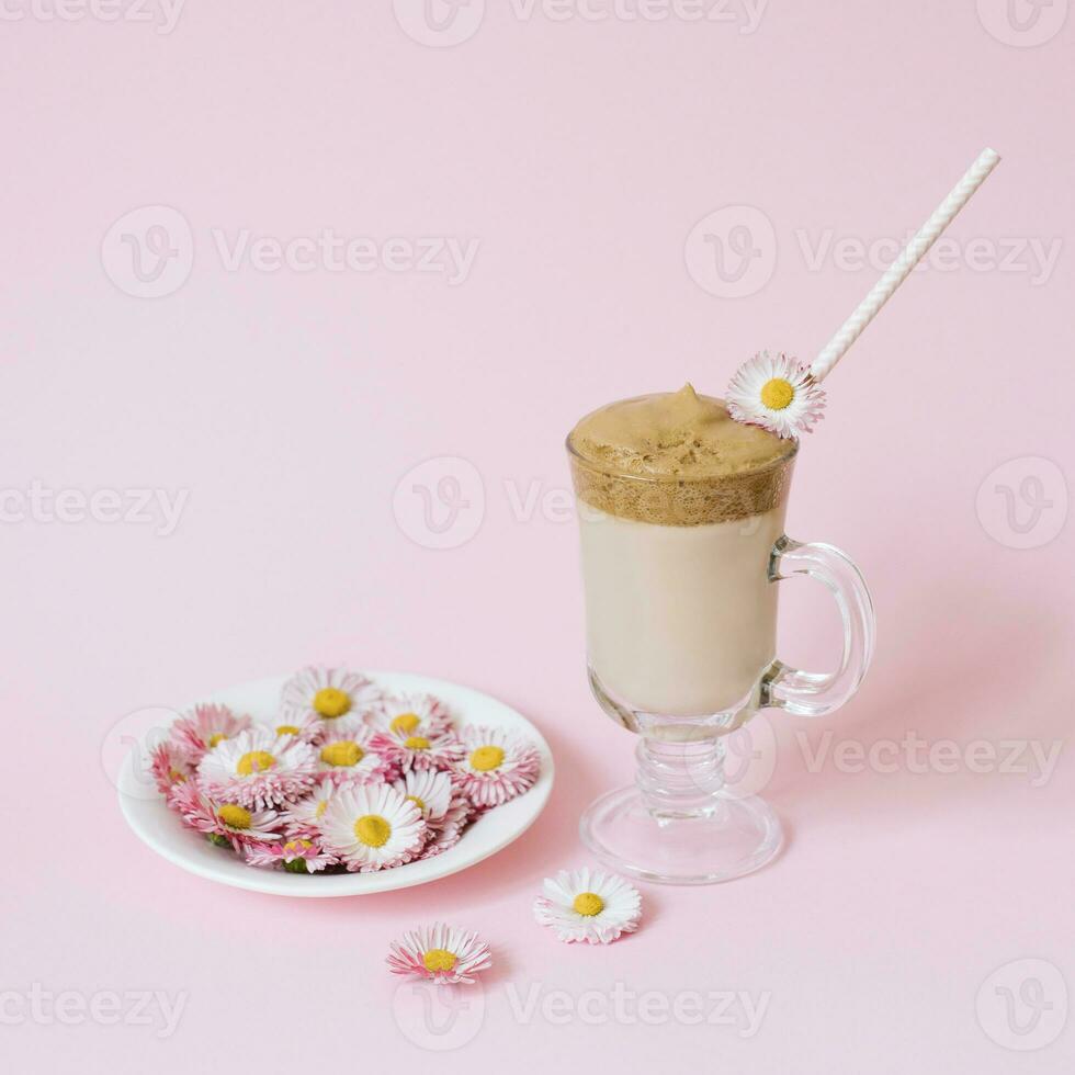 dalgona Coffee in a transparent Cup with a paper tube, a plate with flowers daisies. The concept of a summer drink photo