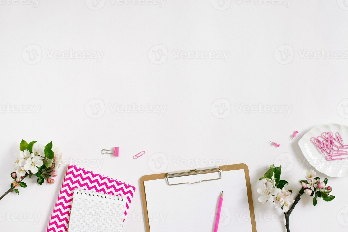 Stylish flat lay women's workplace with notebooks, tablet, pen and spring apple blossoms on a white background with copy space photo