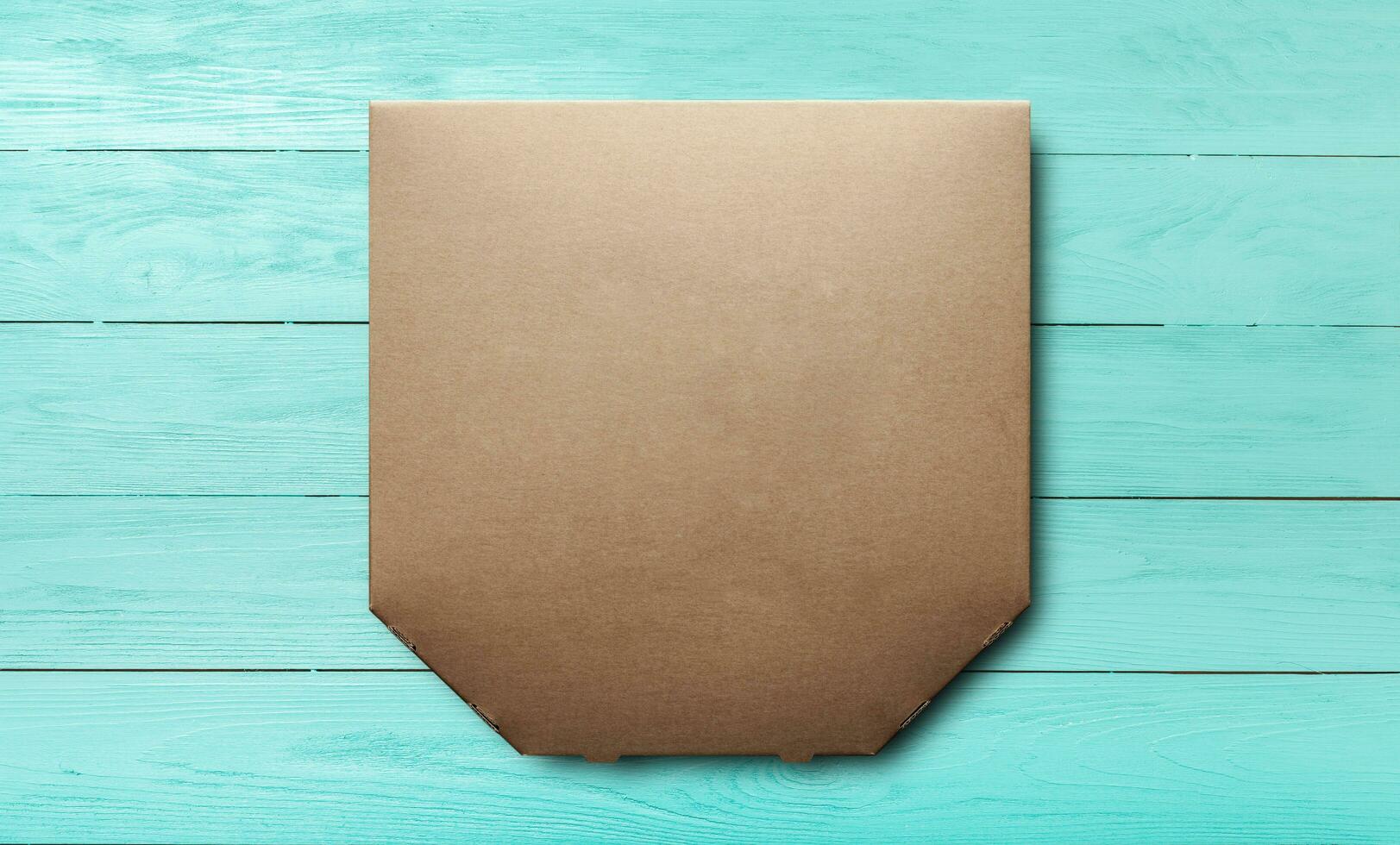 Box of cardboard pizza, blank unprinted on a blue wooden background, mockup top view photo