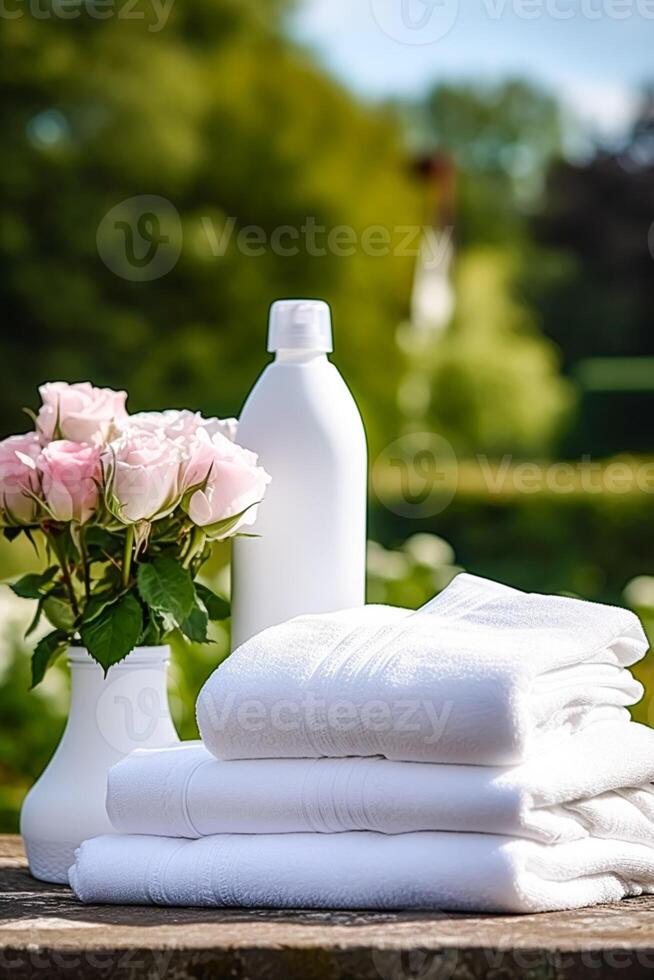 Laundry, housekeeping and homemaking, white clean folded clothes and detergent conditioner bottle in the garden, country cottage style, photo