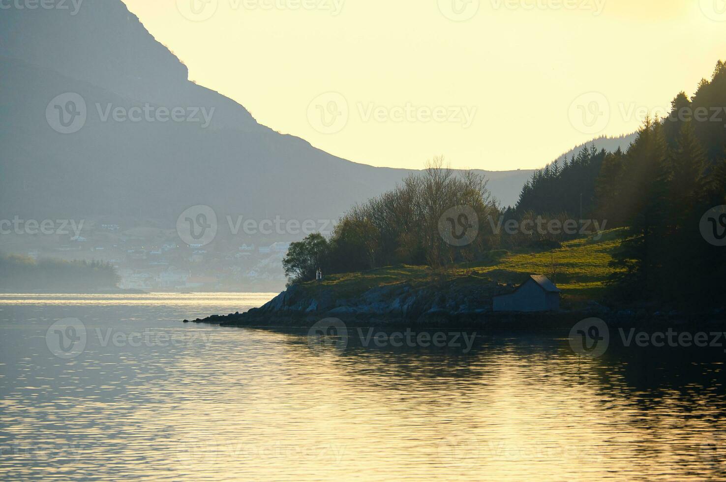 Sunset on the fjord with mountains in Norway. Diffuse light, sun rays on a meadow photo