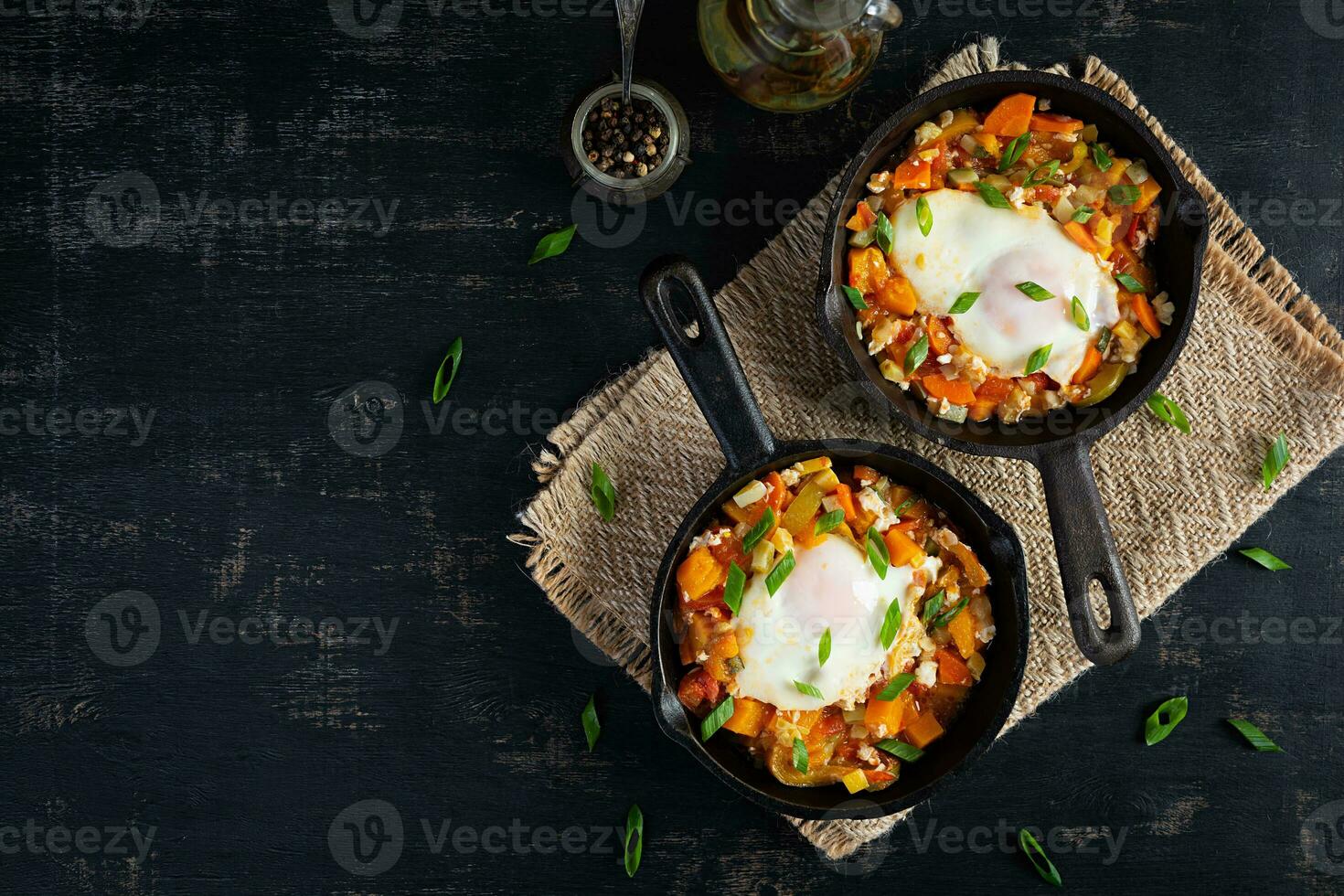 Shakshouka in frying pan. Fried eggs with vegetables, tomato, pepper, pumpkin and onion. Top view photo