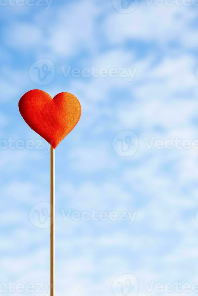 Red heart against blue cloudy sky photo