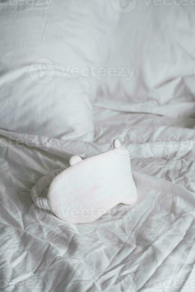 Sleep eye mask lying on white bedding. Awaking or insomnia concept. photo