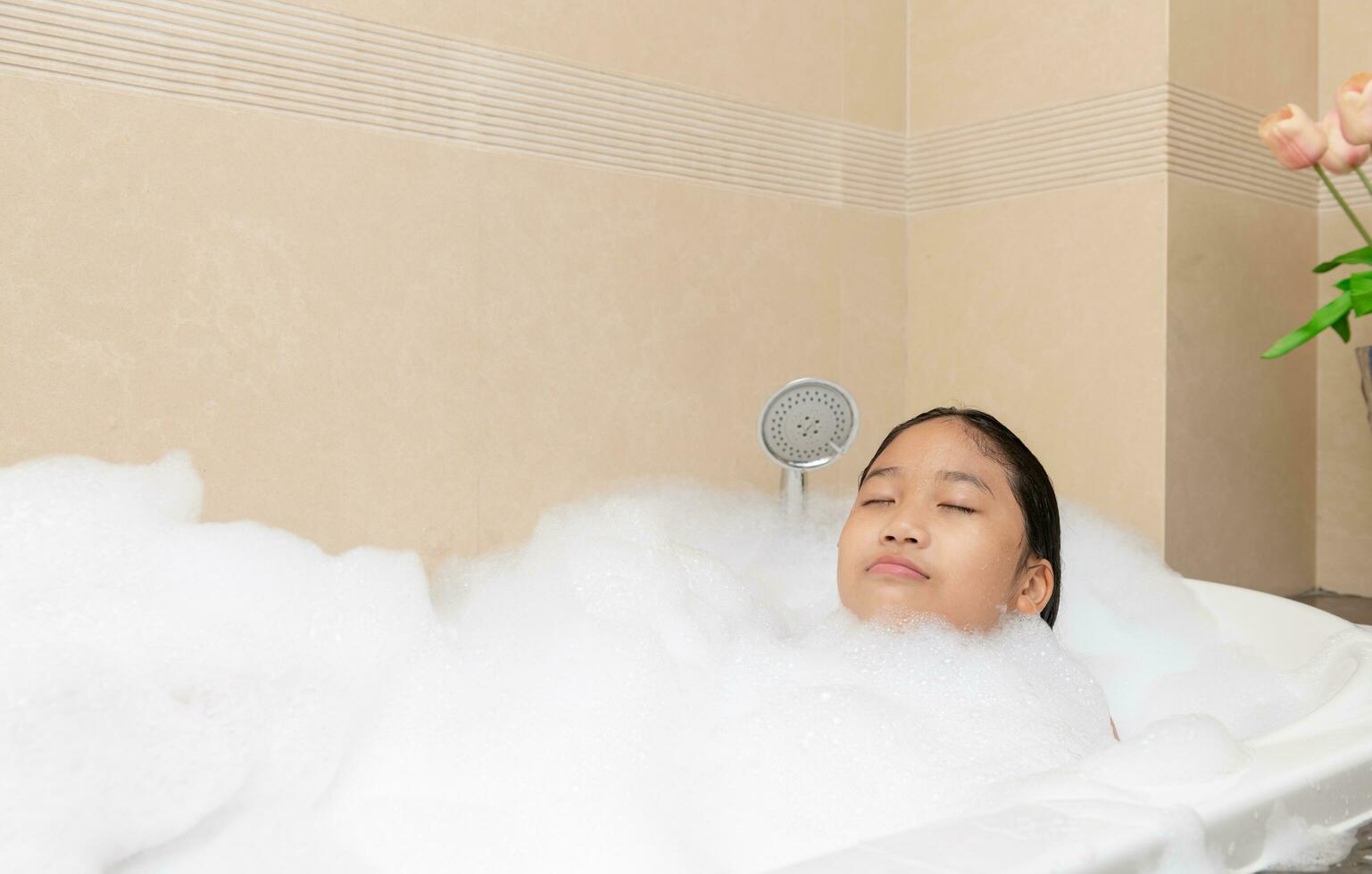 Bathing little girl relaxing in bath smiling relaxing. Caucasian child woman in bathtub. photo