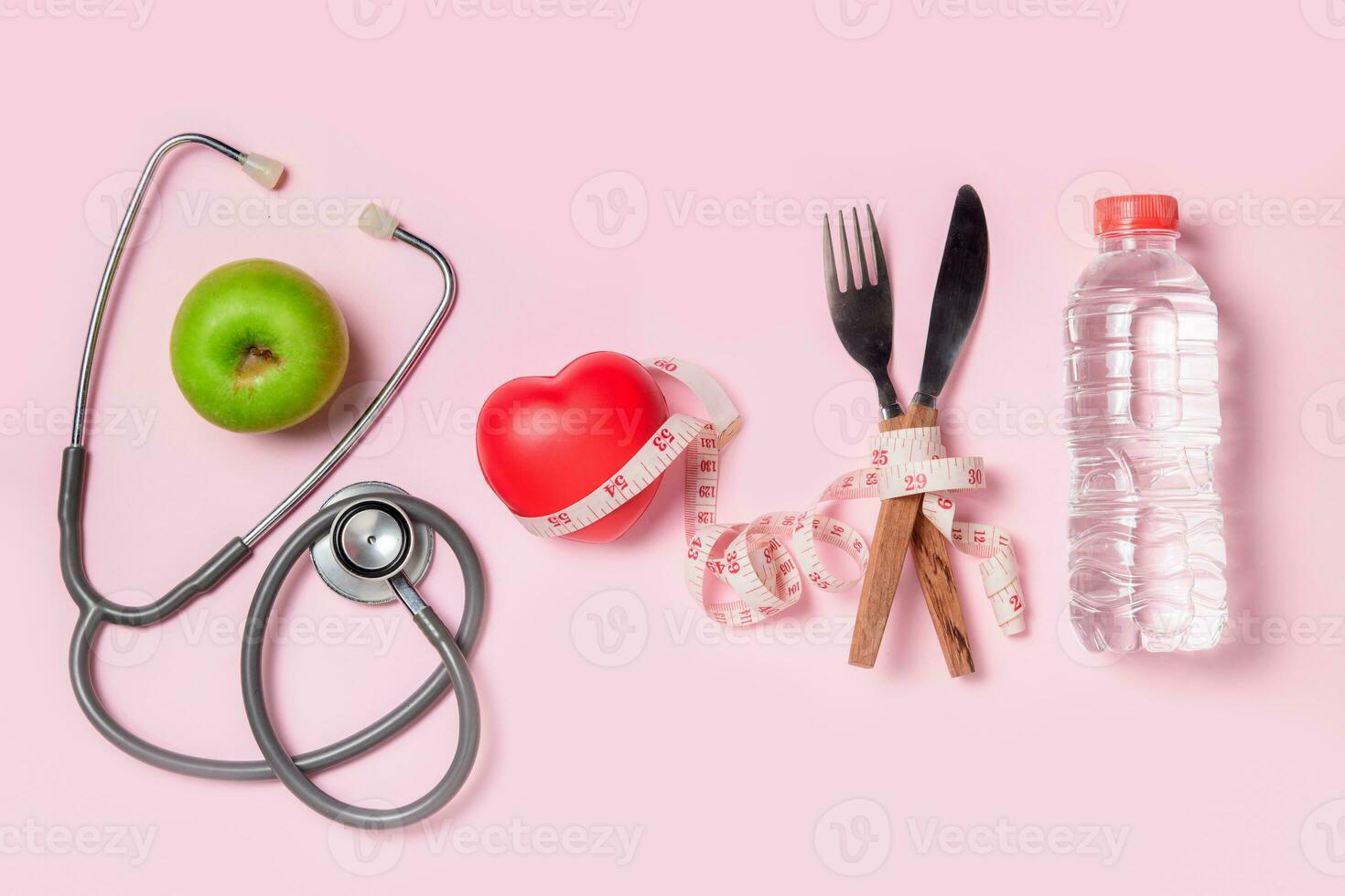 Green apple with stethoscope and measuring tape around fork and knife isolated photo