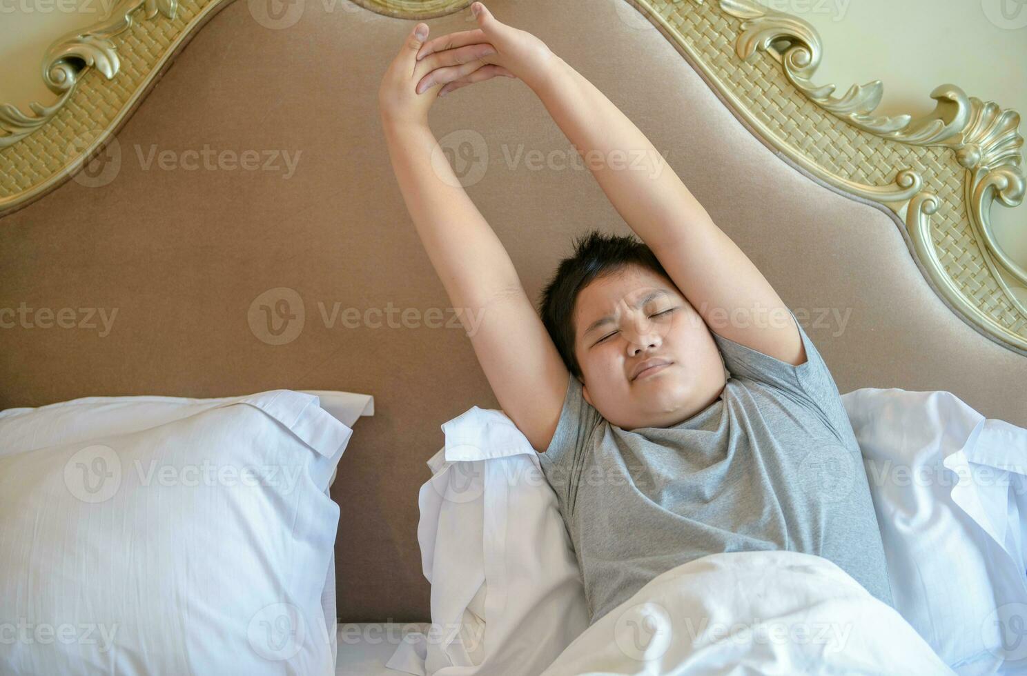 asiático grasa chico despierta arriba y extensión en cama en mañana, foto