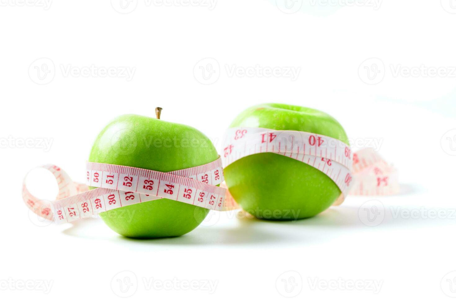 Measuring tape wrapped around two green apple isolated on white  background, photo