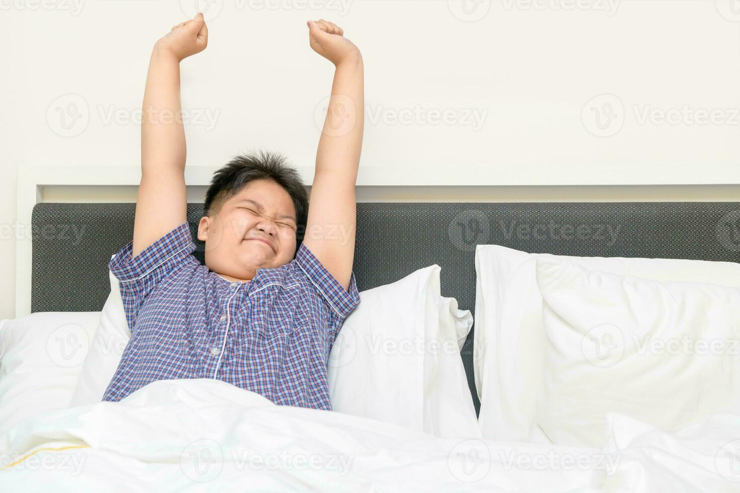 obese fat boy wakes up and stretching on bed in morning, photo
