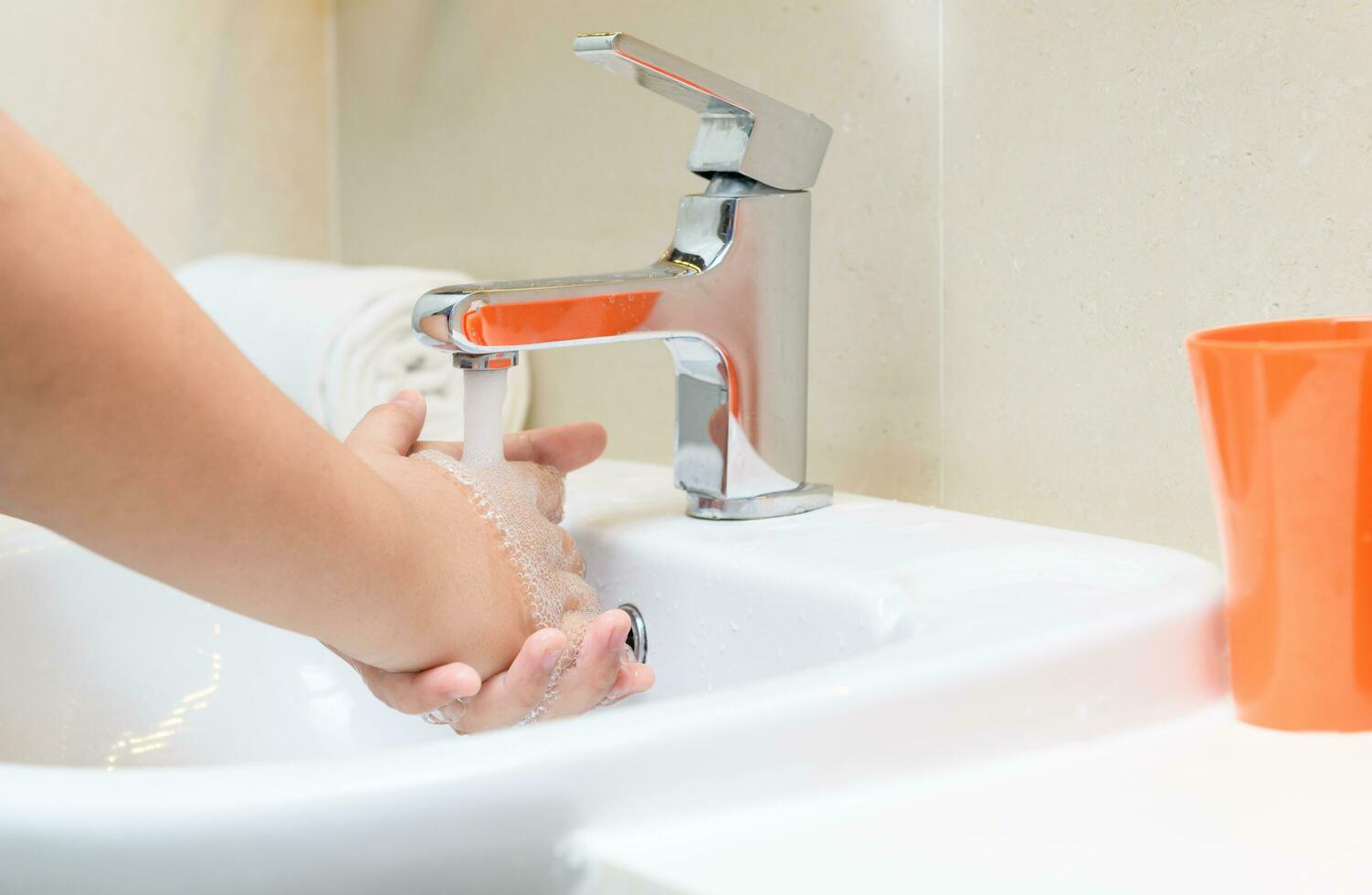 Washing hands child rinsing soap with running water at sink, photo