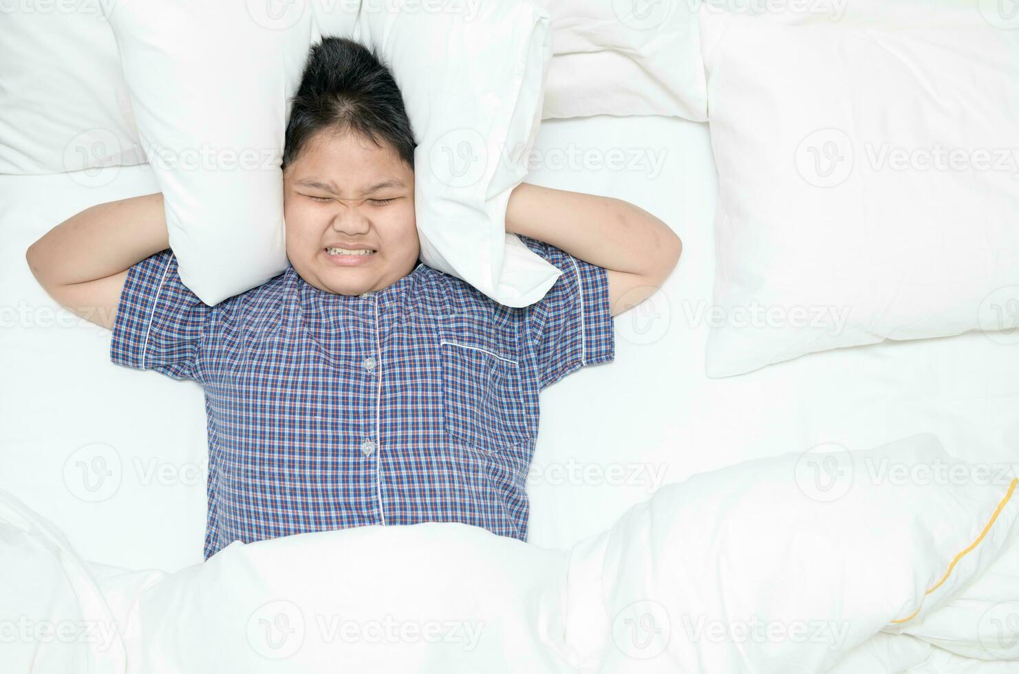 Fat boy covering head with pillow because too loud annoying noise. photo