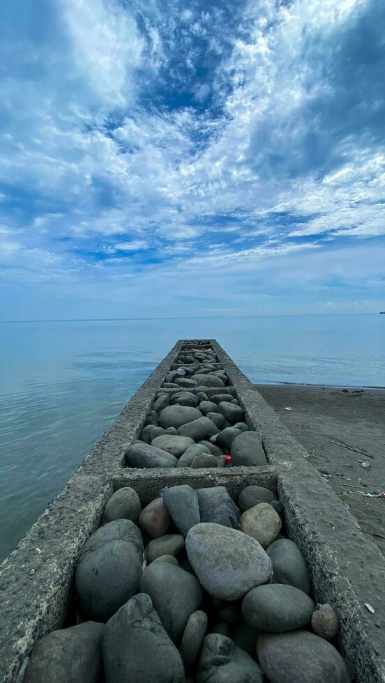 pila de piedras en el playa con azul cielo y nubes en el antecedentes foto