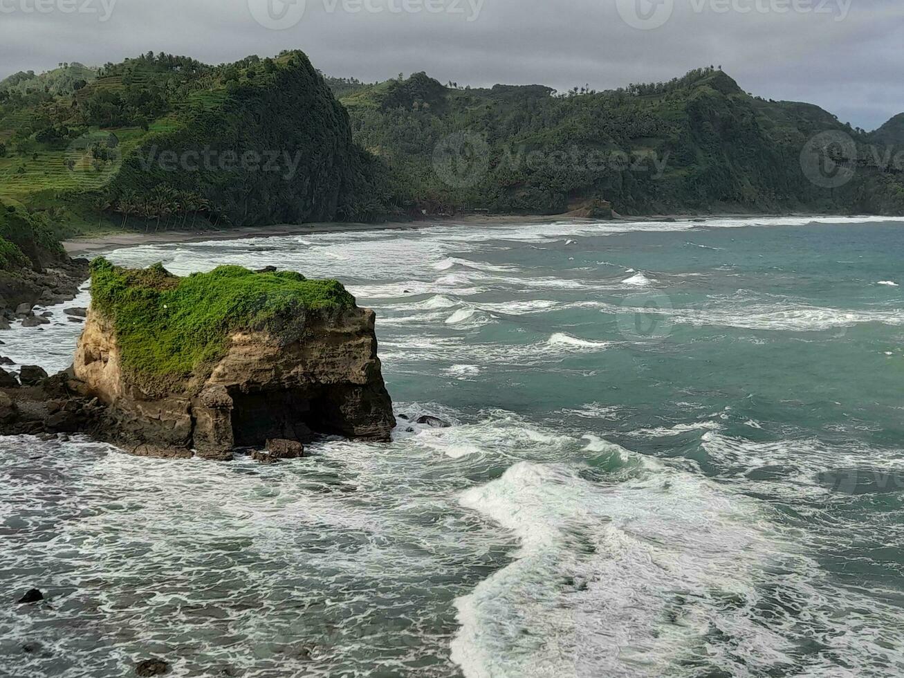 beach with a cliff in the background and a green hill background. photo