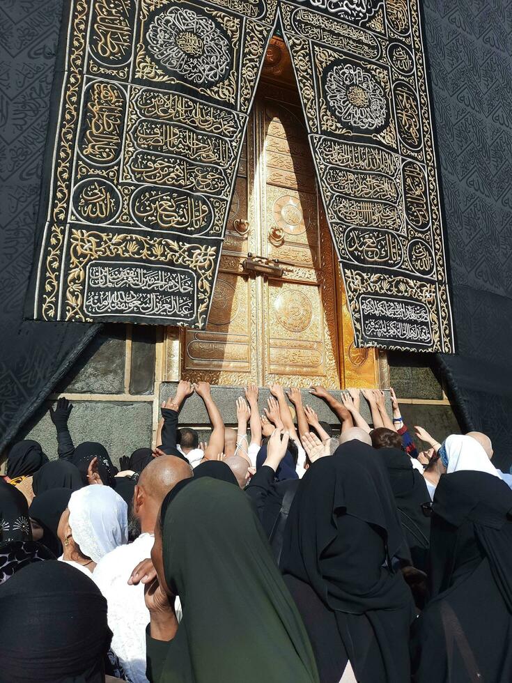 Mecca, Saudi Arabia, April 2023 - Umrah pilgrims from all over the world gather in the courtyard of Masjid al-Haram near the door of the Kaaba. photo