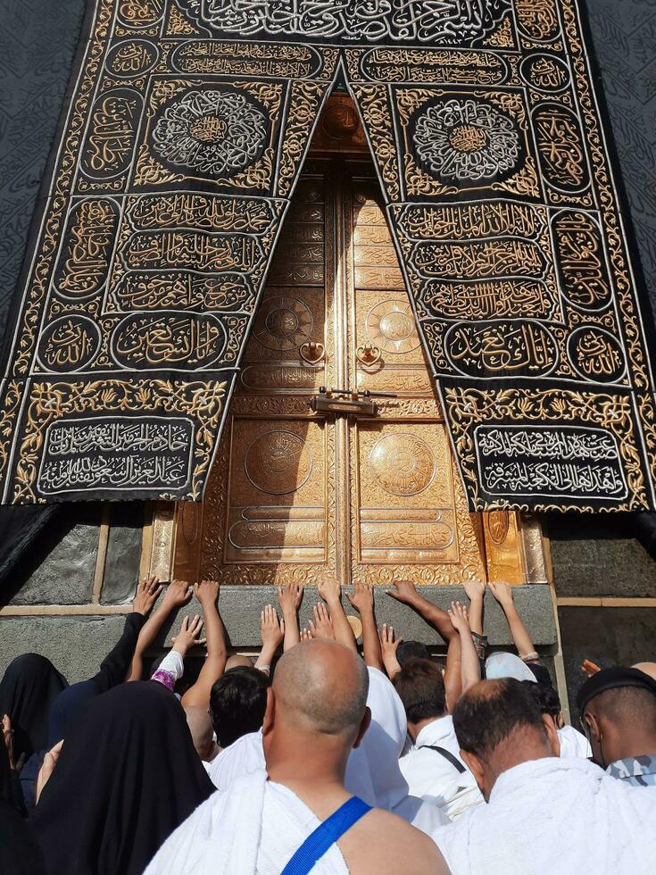 Mecca, Saudi Arabia, April 2023 - Umrah pilgrims from all over the world gather in the courtyard of Masjid al-Haram near the door of the Kaaba. photo