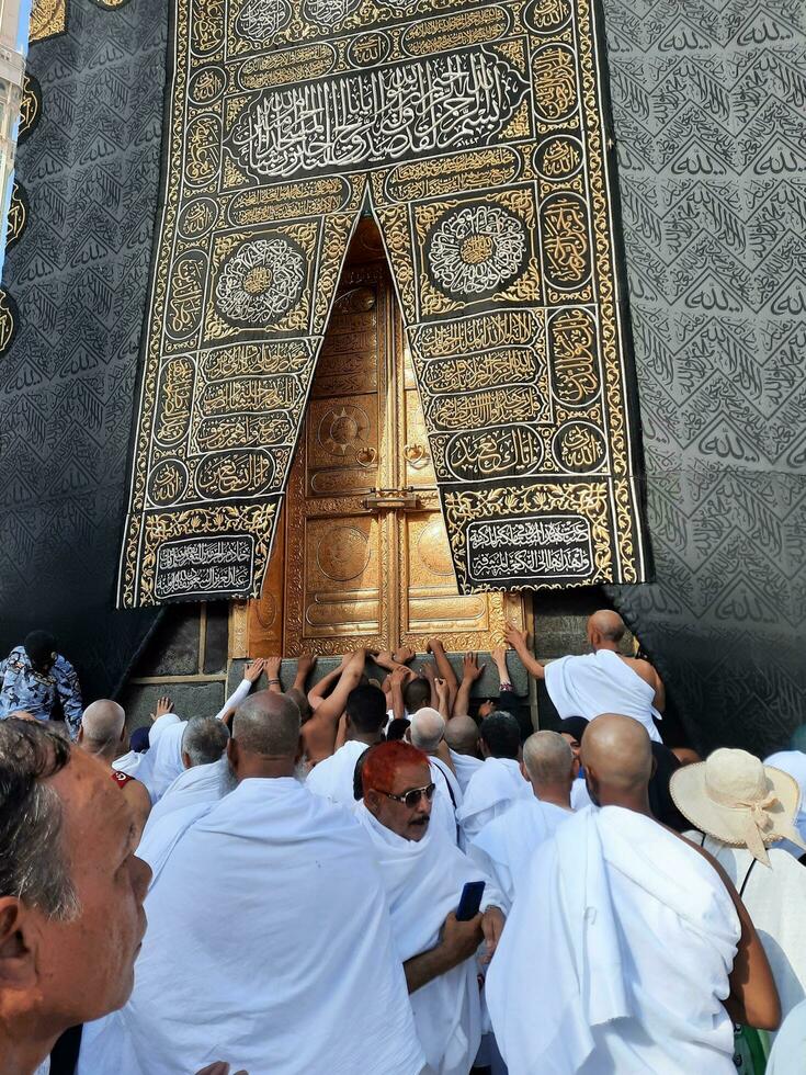 Mecca, Saudi Arabia, April 2023 - Umrah pilgrims from all over the world gather in the courtyard of Masjid al-Haram near the door of the Kaaba. photo