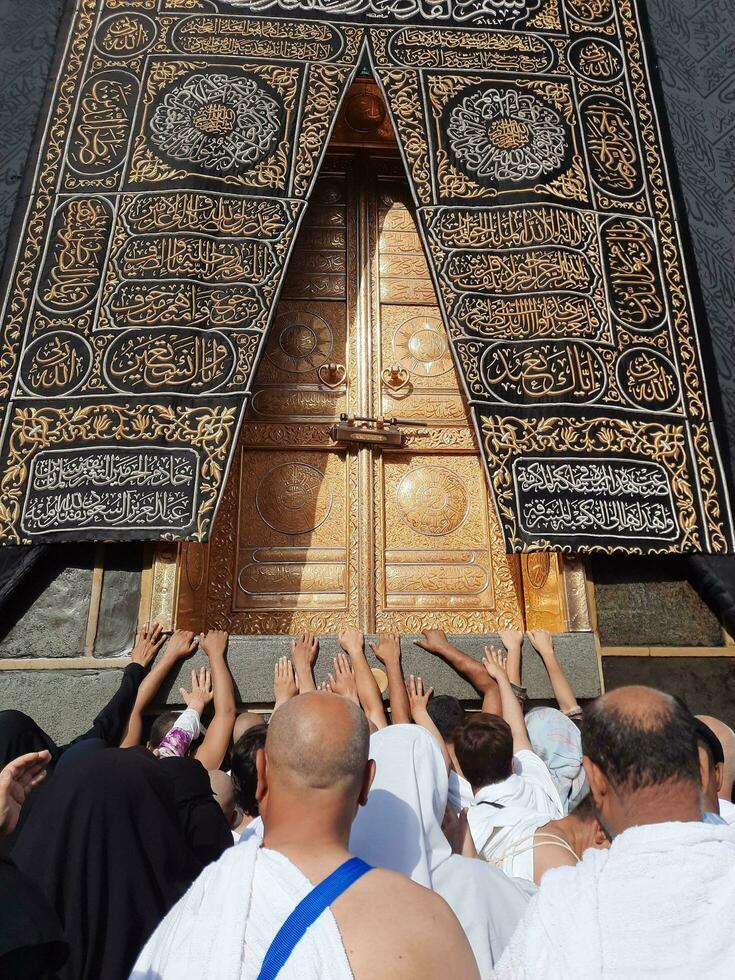 Mecca, Saudi Arabia, April 2023 - Umrah pilgrims from all over the world gather in the courtyard of Masjid al-Haram near the door of the Kaaba. photo