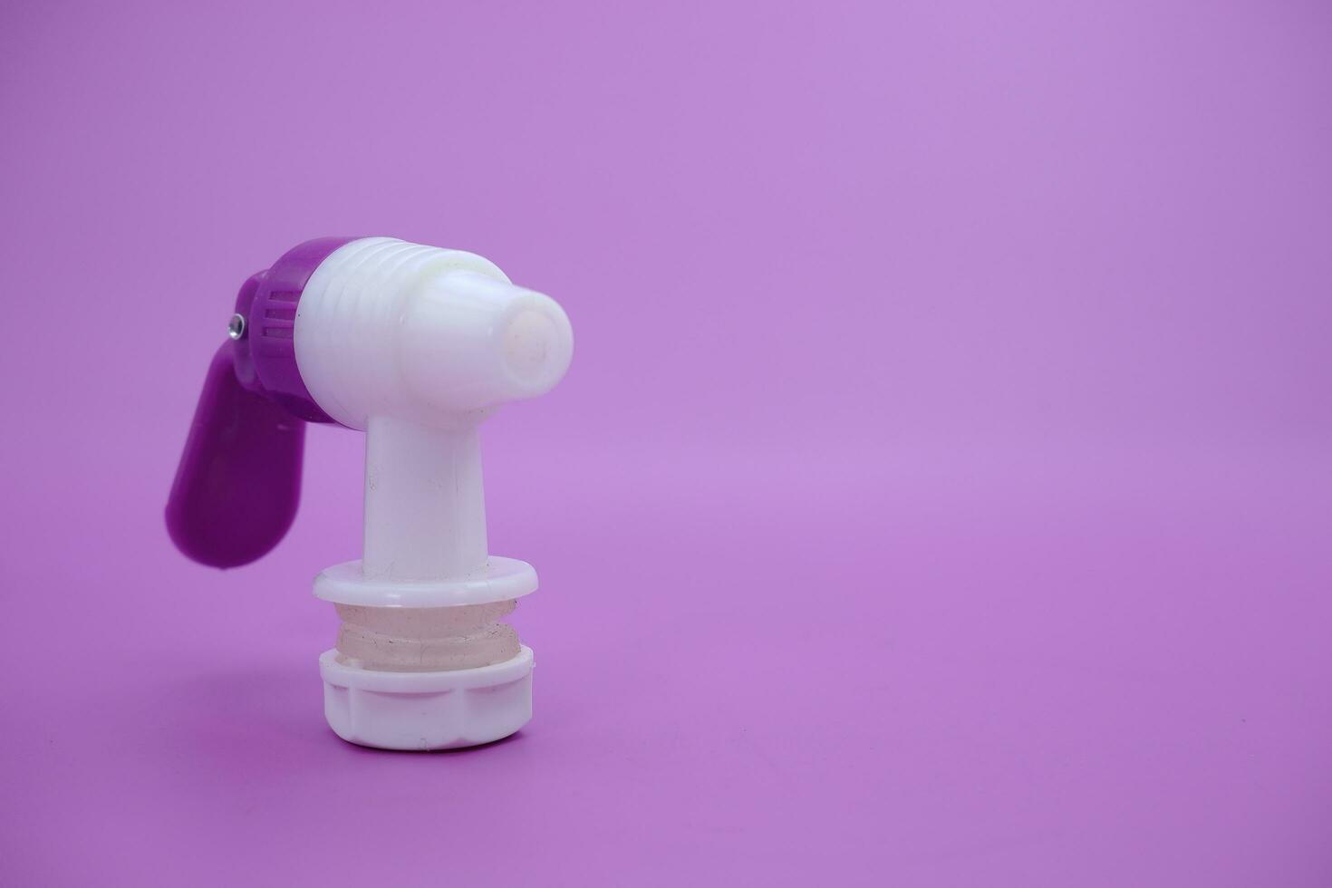 closed faucet isolated purple background. the faucet is white with a purple lid photo