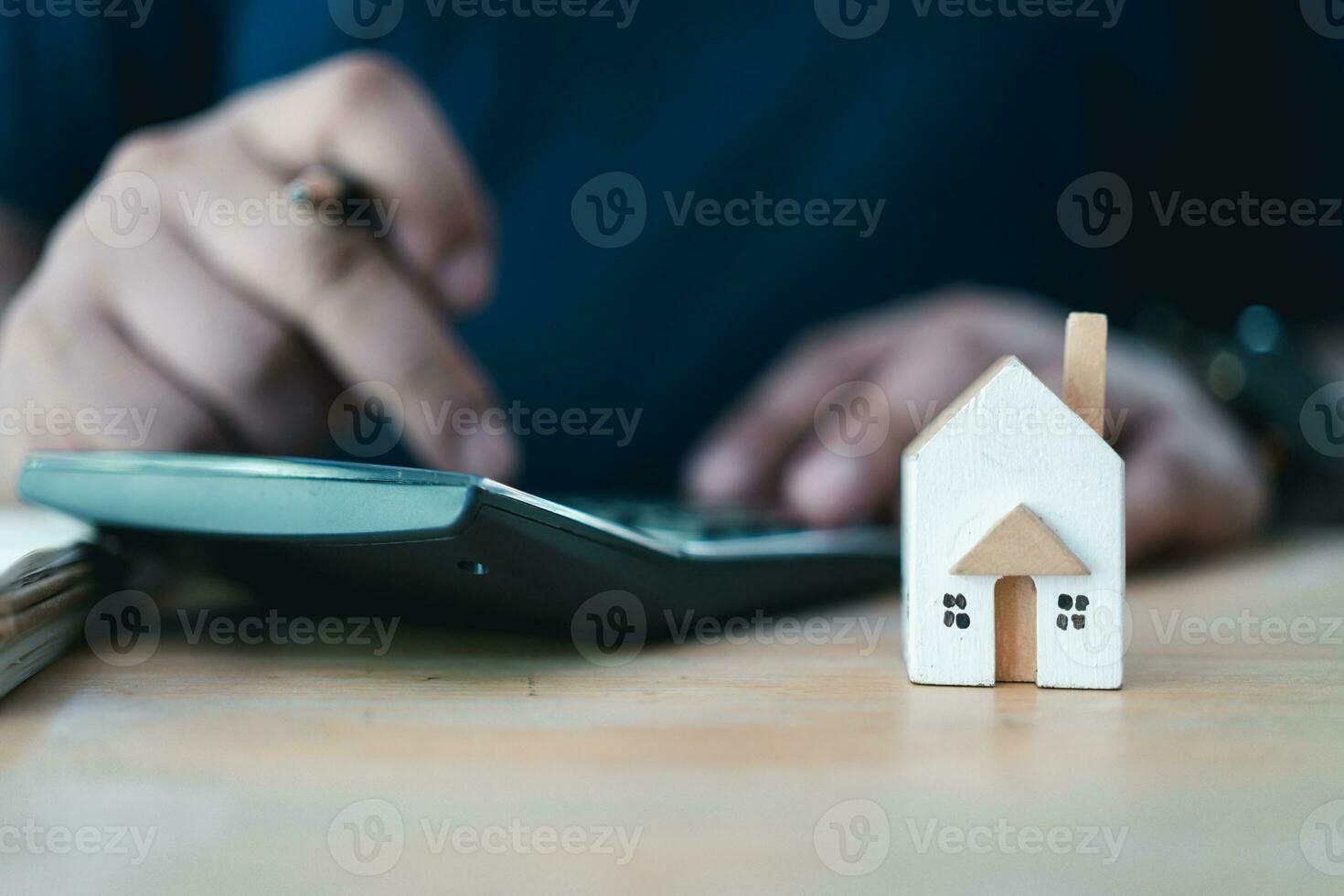 Man using calculator to calculate financial data with miniature wood