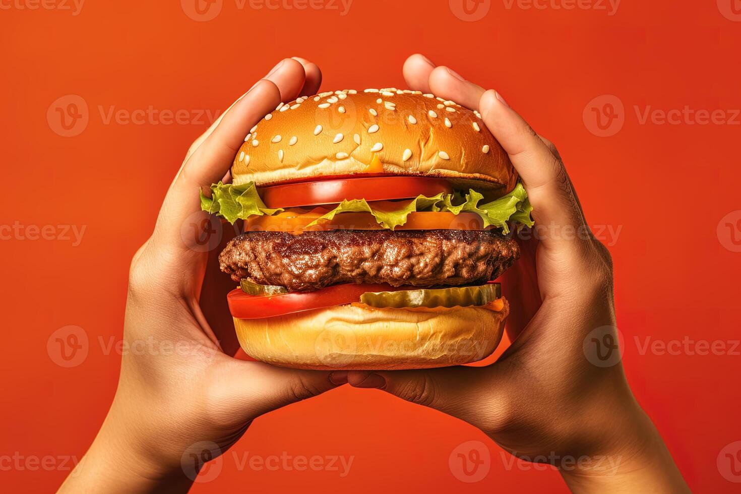 Hands holding a hamburger isolated on orange background. photo