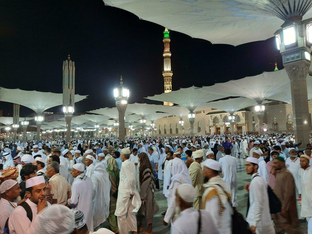 Medina, Saudi Arabia, May 2023 - Beautiful night time view of Masjid Al Nabawi, Medina. Visitors, courtyards outside the mosque, beautiful lights and electronic umbrellas can also be seen. photo