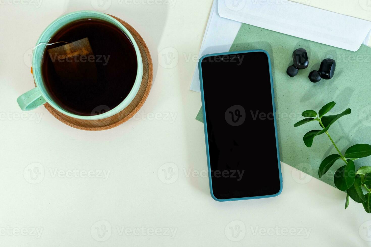 Image with smart phone, paper, envelope and tea cup on white background. Home office scene, flat lay, top view. photo