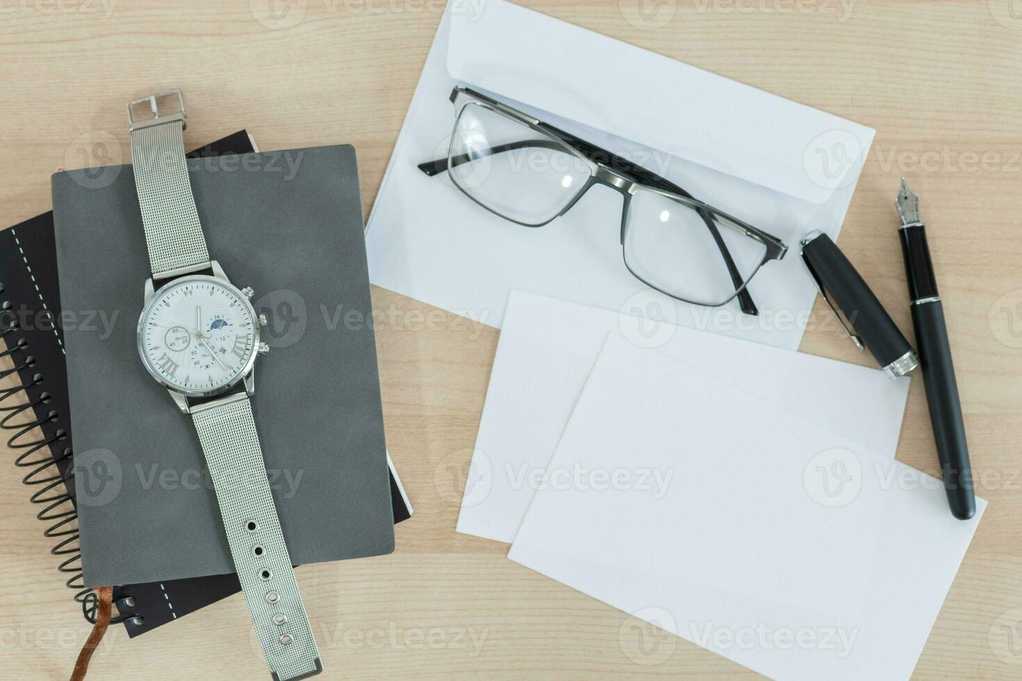Identity design mockup. Notepad, eyeglasses, pen, card, envelope, watch on wooden office desk. photo