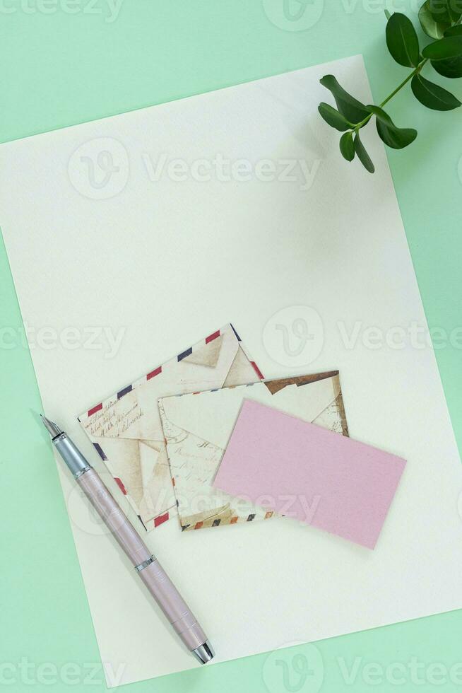 Top view of envelope and blank greeting card with pen on green background. photo