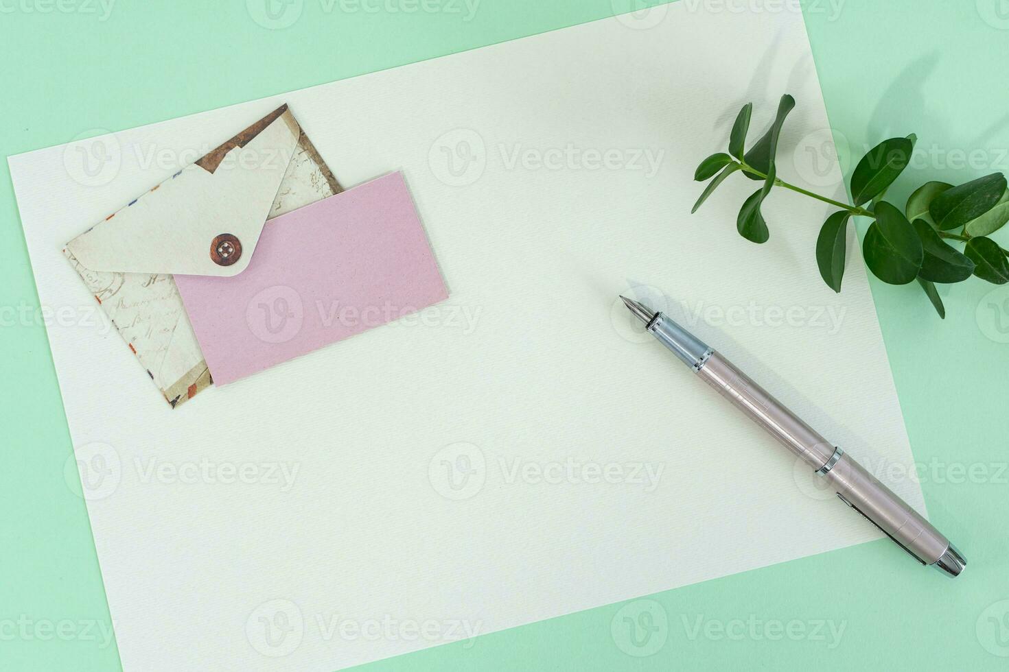 parte superior ver de sobre y blanco saludo tarjeta con bolígrafo en verde antecedentes. foto