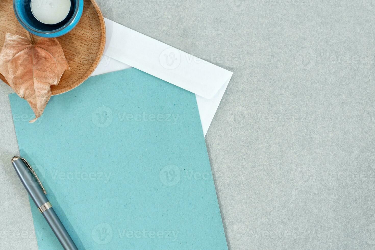 Blank blue memo pad with pen, candle and wooden dish on gray background. photo