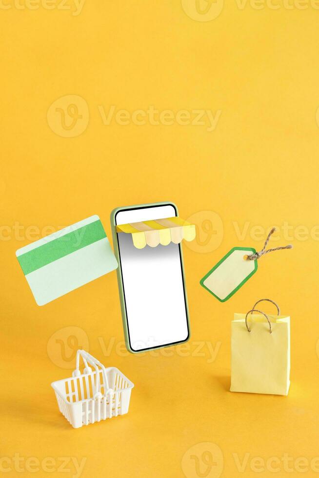 The shopping basket, credit card and bag floating out of the online store on a yellow background. photo